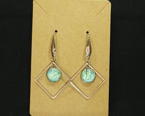 soft streaks of green white and blue pour painted under glass set in stainless steel.